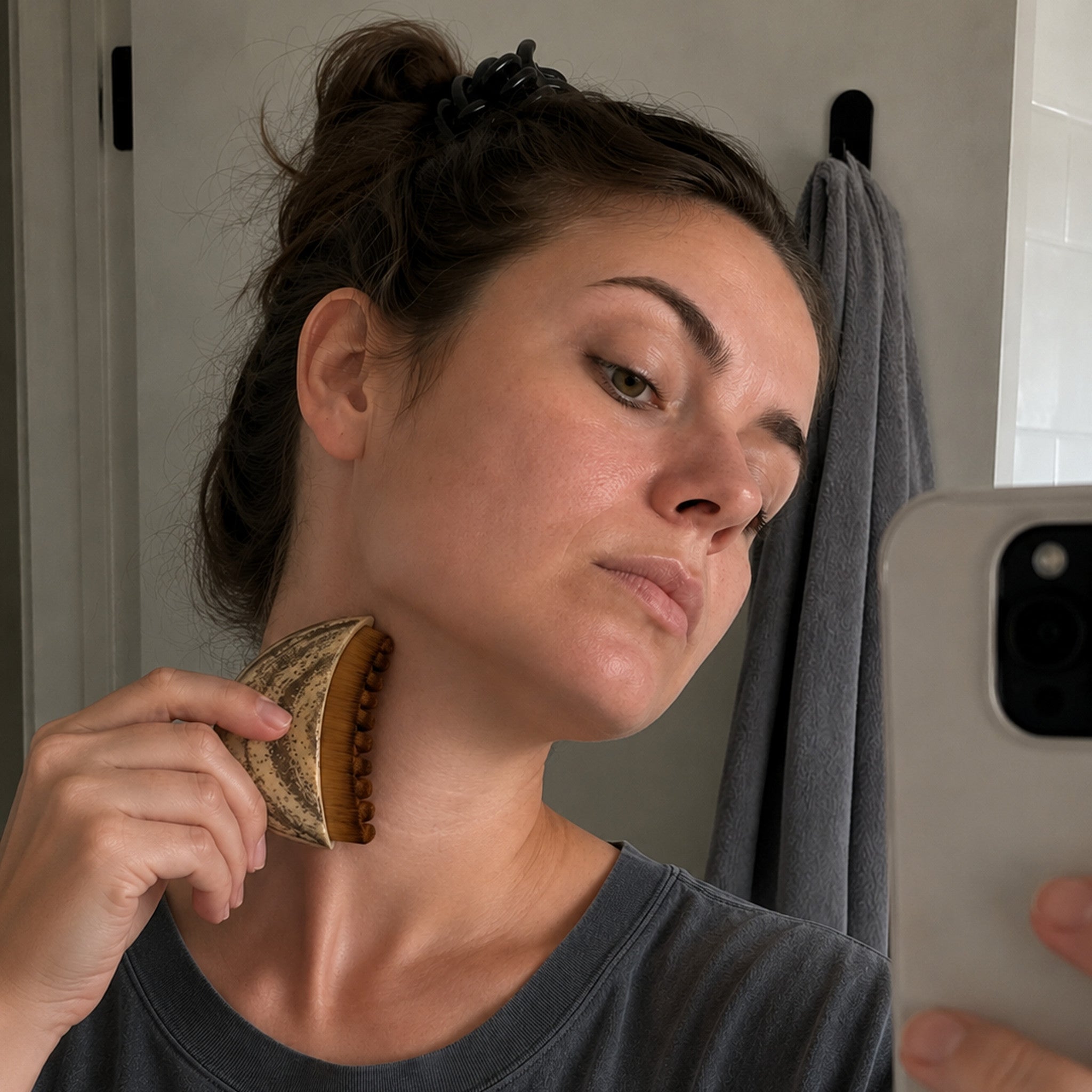 Woman drawing the Cueva Contour Brush down the side of her neck, just below the jaw